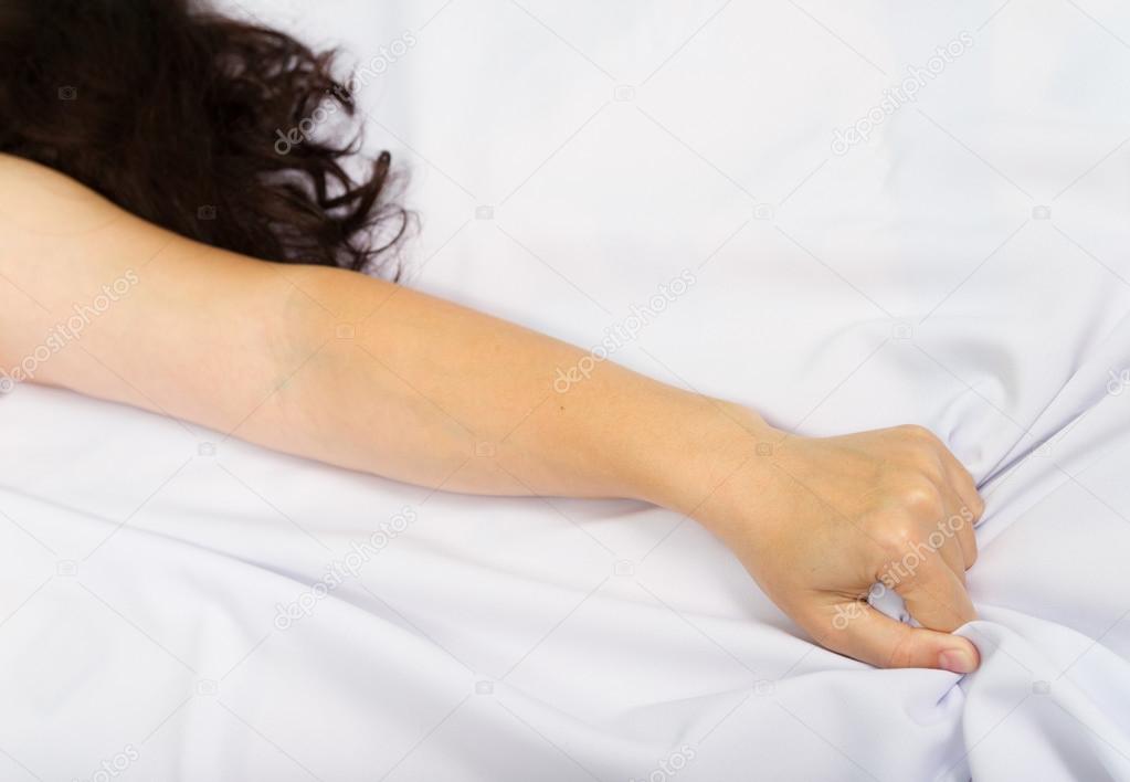 Female hand pulling white sheets in ecstasy
