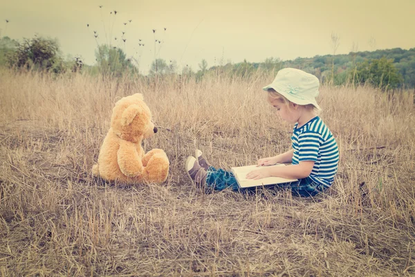 Niedliches Mädchen liest Buch Teddybär — Stockfoto