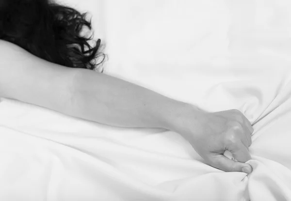 Женская рука тянет белые простыни в экстазе — стоковое фото