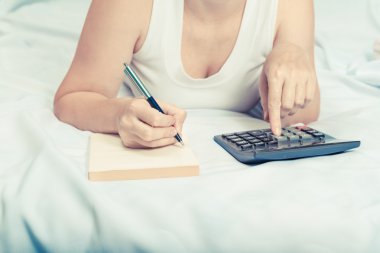 yatakta bir defter ve hesap makinesi kredi ile genç kadın, mo