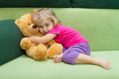 Little girl hugging a Teddy bear. clipart
