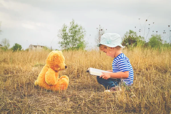 Niedliches Mädchen liest Buch Teddybär — Stockfoto