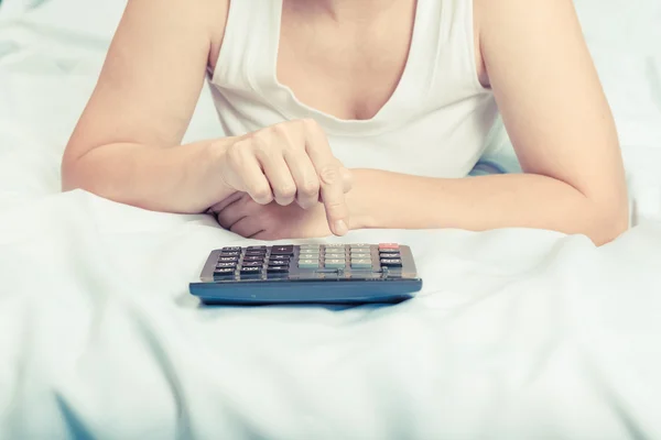 Młoda kobieta w łóżku z kalkulatorem. Budżetu rodzinnego. Kredyt, — Zdjęcie stockowe