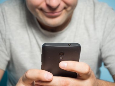 Gri bir t-shirt smartphone içinde beyaz delikanlı 