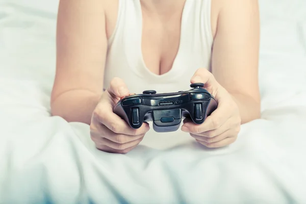 Jovem mulher caucasiana jogando console de videogame na cama — Fotografia de Stock