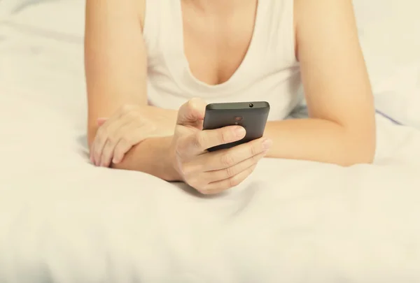 Młoda kobieta kaukaski na łóżku z smartphone — Zdjęcie stockowe