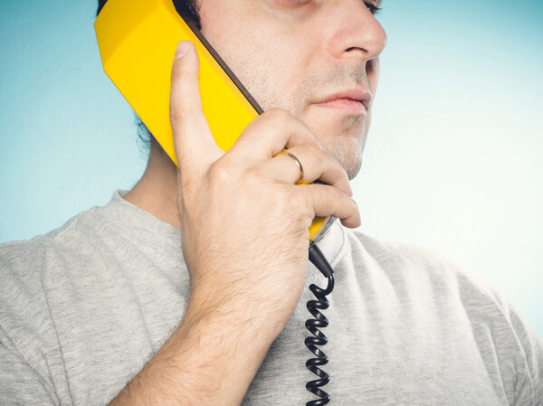 Caucasian man talking on a landline phone.