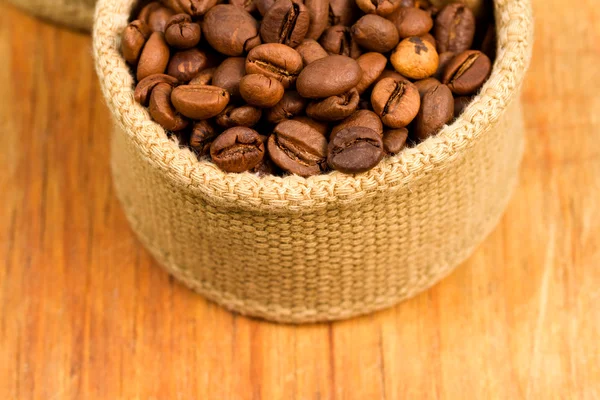 Grãos de café em tecido em uma madeira — Fotografia de Stock