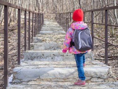 Merdivenlerden yukarı gidiş bir sırt çantası ile küçük kız.