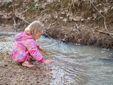 Nehir kıyısında oturan sevimli küçük kız