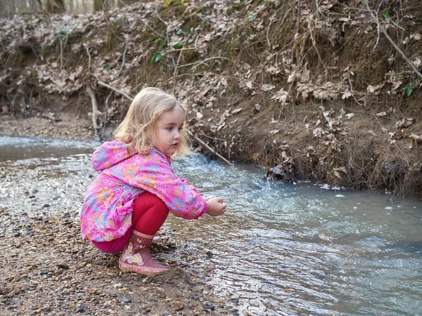 Carina bambina seduta sulla riva del fiume — Foto Stock