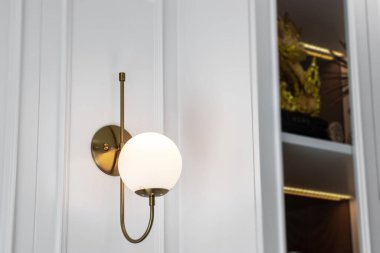 Beyaz duvarda altın duvar lambası