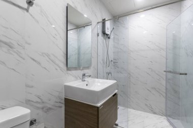 Su ısıtıcısı ve duş kabini olan küçük beyaz bir banyo. 