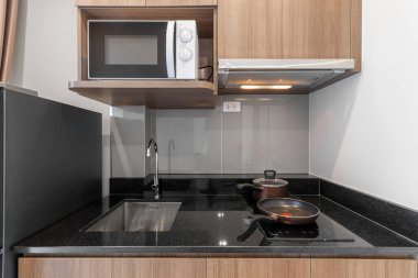 Odasında mikrodalga fırın ve elektrikli ocak olan ahşap mutfak. 