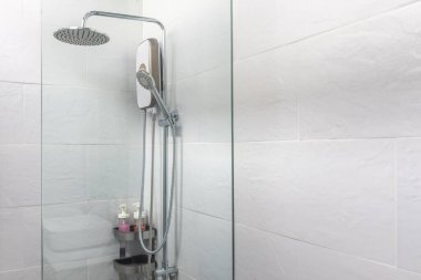 Banyoda duş ve cam kapı, beyaz fayans odası.