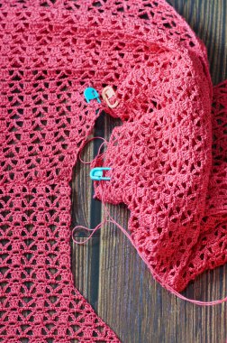 Koyu ahşap arka planda pembe pamuk ipliklerle tığ işi. Pembe pamuklu örgü işi. Tahta masada tığ işi desenleri var. Tığ işi örgü işi. Yakın plan.. 