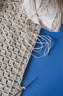 Mavi arka planda bej pamuklu örgü. Basit tığ işi deseni. 