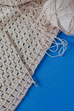 Mavi arka planda bej pamuklu örgü. Basit tığ işi deseni. 