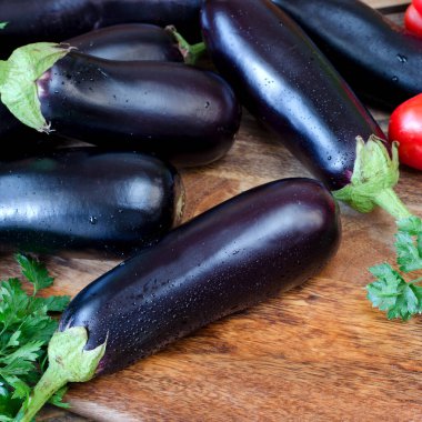 Tahta kesme tahtasındaki birkaç ürünün görüntüsü. Çiğ sebzeler ve bahçedeki bitkiler. Organik hasat. Patlıcan, soğan, kırmızı dolma biber, maydanoz karışımı..