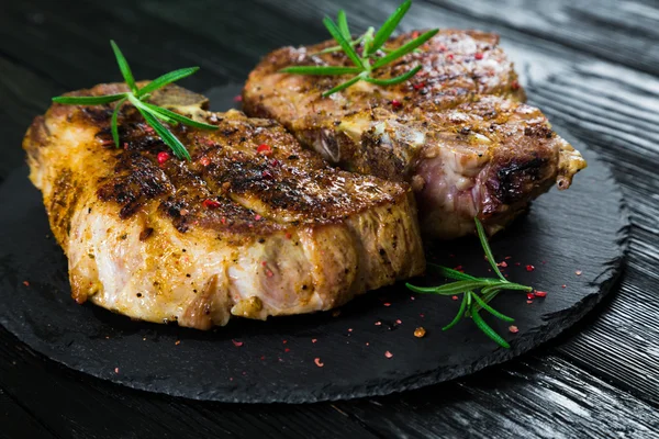 Bistecca di maiale alla griglia sul tavolo nero — Foto Stock