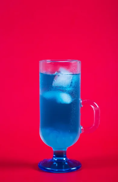 Освіжаючий синій коктейль на червоному тлі — стокове фото