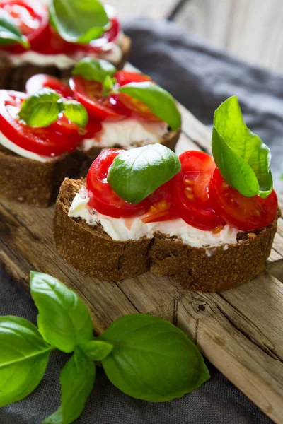 Bruschetta cu cremă de brânză roșii cherry și busuioc — Fotografie, imagine de stoc