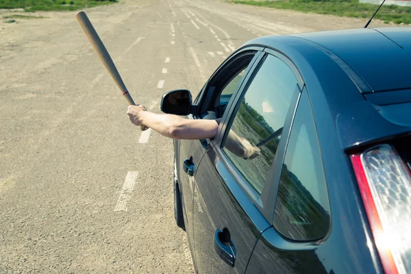 Man with baseball bat on the road before the car — Stock Fotó