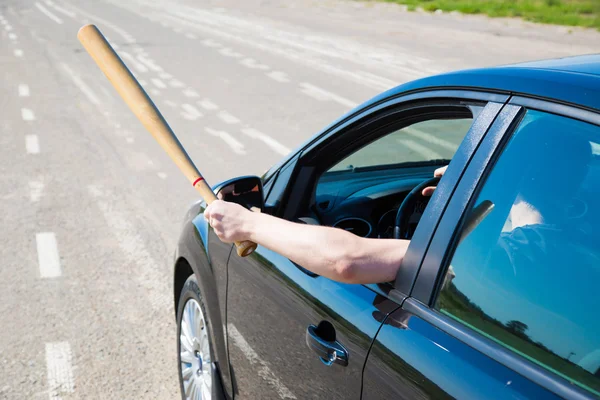 Man with baseball bat on the road before the car — Stock Fotó