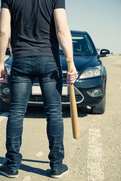 Man with baseball bat on the road before the car — Stock Fotó