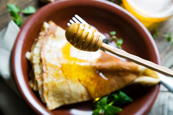 Pannkakor med honung på ett träbord — Stockfoto