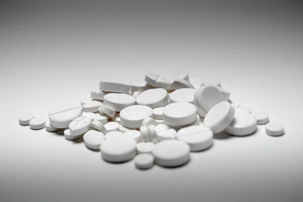 Pile of white tablets, shot on white with shadows and graded illumination — Stock Photo, Image