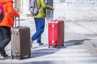 Turistler bavullarıyla sokakta yürüyorlar.