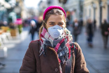 Virüs ve kirlilikten korunmak için maske takan genç bir kadın.