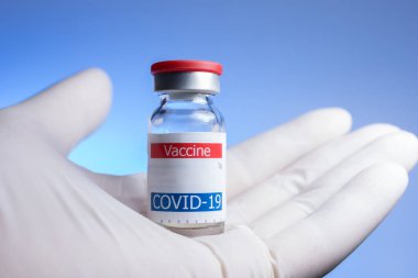 Eldivenli el Coronavirus aşı şişesini tutuyor.