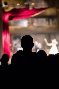 Seyirciler tiyatroda bir oyun izliyor.