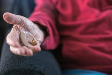 Yaşlıların elleri işitme cihazını tutuyor