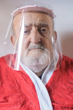 Koruyucu güneşlik ve Noel Baba kıyafeti giyen yaşlı bir adam.