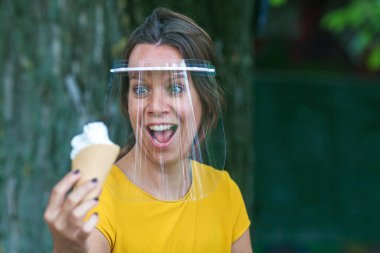 Koruyucu güneşlik takan ve elinde dondurma tutan genç bir kadın.