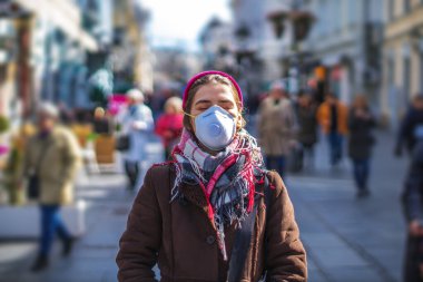 Virüslerden ve kirlilikten korumak için maske takan genç bir kadın.