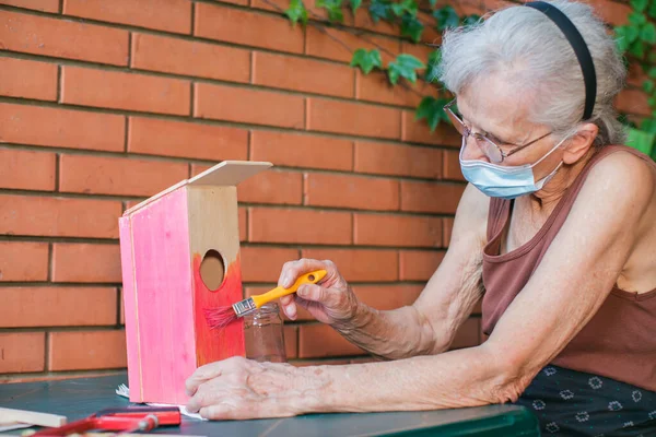 Anciana Con Mascarilla Pintando Una Pajarera — Foto de Stock