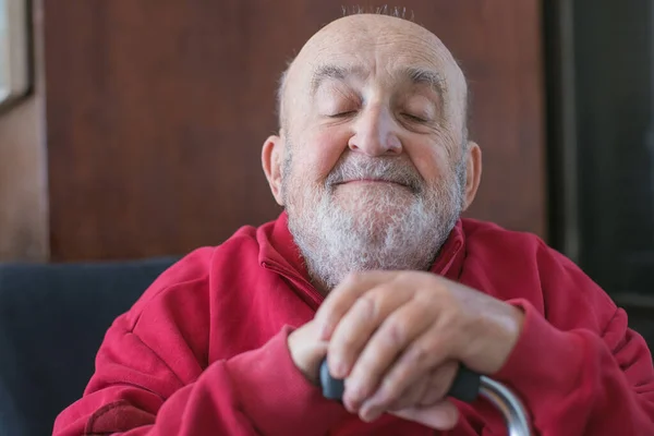 old man sitting with walking stick in his hand