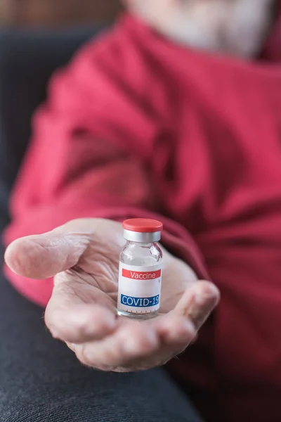 coronavirus vaccine vial in elderly person's hand