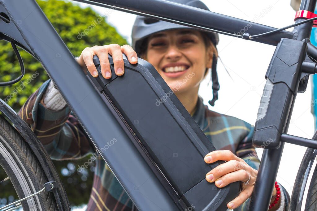 young woman holding an electric bike battery mounted on frame