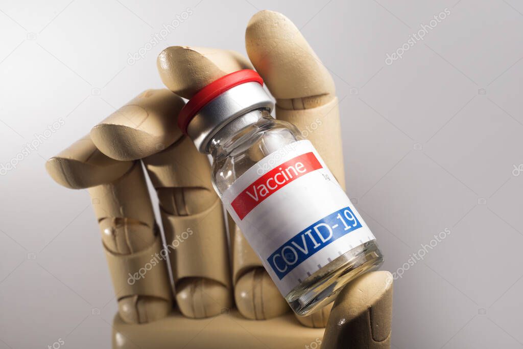 artificial hand holding coronavirus vaccine vial