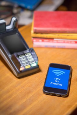 Kitapçıda ankesörlü telefon kullanıyor.