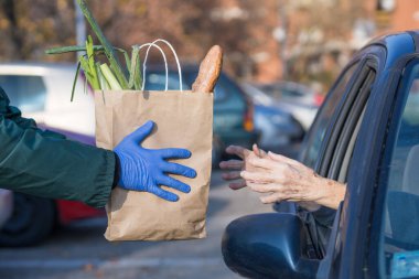 paper bag with groceries handed to needy elderly person in vehicle clipart