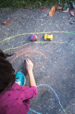 Çocuk parkta küçük araba oyuncaklarıyla oynuyor.