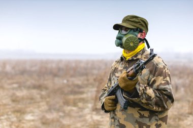 Gaz maskeli ve otomatik silahlı asker hazır bekliyor.