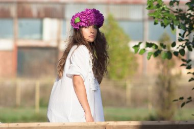 Kafasında çiçek çelengi olan gülümseyen hippi kız.