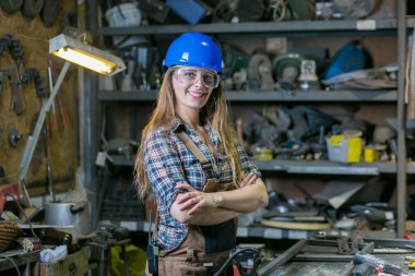 Atölyede poz veren kasklı genç bir kadın.